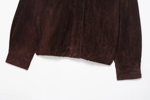 Dettaglio di una giacca scamosciata marrone scuro con bordo elastico e tasche laterali