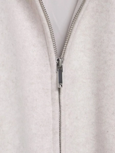 Détail du zip en métal argenté sur un tissu en polaire épais de couleur blanc cassé