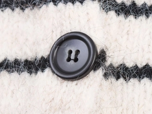 Detailed macro view of black buttons on fuzzy black and white striped knit cardigan