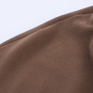 Detailed macro view of dark brown knitted fabric texture and fine stitching on the dress