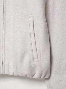 Gros plan sur la veste texturée avec fermeture éclair en métal et poche passepoilée