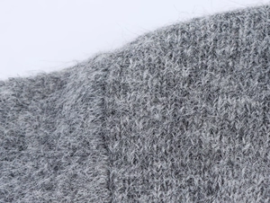 Dettaglio macro del tessuto a maglia grigio scuro con texture mohair e fibre calde