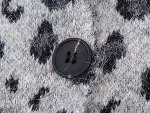 Macro shot of fluffy leopard jacquard knit fabric and textured black resin button