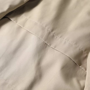 Detail of khaki cropped trench coat showing high-quality stitching and woven fabric texture