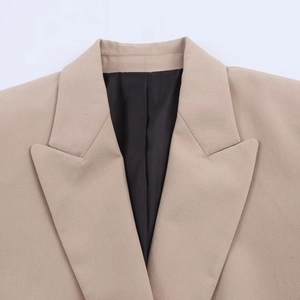 Detailed close-up of peak lapels and khaki twill fabric on a structured blazer
