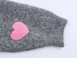 Dettaglio del tessuto grigio in maglia con una toppa a cuore rosa a rilievo