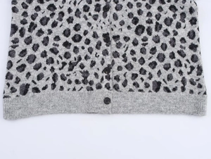 Close-up of leopard pattern knit cardigan with textured buttons and ribbed hem detail