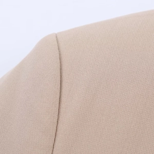 Detail view of precise shoulder seam and woven texture on this beige blazer jacket