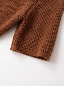 Macro shot of vertical ribbed knit texture on a thick caramel brown winter sweater