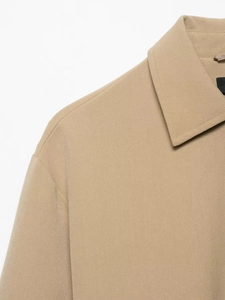 Détail d'une veste marron clair avec col pointu et coutures précises sur le tissu