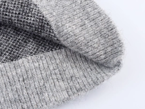 Close-up detail of soft grey leopard jacquard knit texture and ribbed sweater cuff