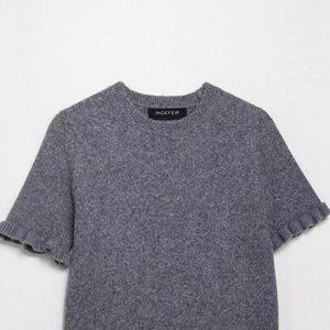 Maglione in maglia grigia a maniche corte con girocollo e dettagli eleganti di volant