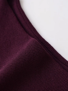 Macro shot of dark purple knitted fabric texture showing premium weave and soft material