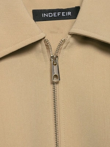Détail de la fermeture éclair en métal et du col pointu classique de veste beige