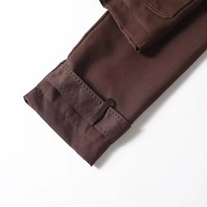 Detailed macro view of dark brown trench coat sleeve cuff with adjustable strap and stitching