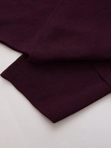 Macro detail of the fine-knit burgundy poncho sweater showing soft texture and fabric