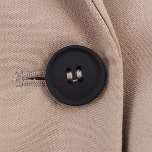 Macro detail of black button on light brown textured wool blazer fabric with stitching