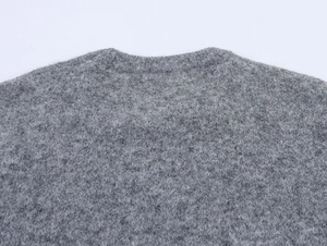 Dettaglio del girocollo e della morbida consistenza pelosa di questo maglione grigio in maglia