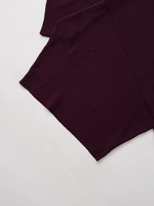 Detail shot of the vertical ribbed knit texture on the dark purple asymmetric poncho sweater