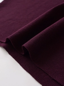 Macro shot of dark purple knit fabric showing high-density texture and soft folds