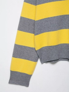 Close-up detail of yellow and grey striped knit texture with ribbed cuffs on polo sweater