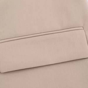 Detailed macro view of beige woven blazer fabric texture and flat pocket flap stitching