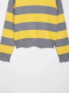 Detail of yellow and gray striped knit sweater showing ribbed cuffs and textured fabric hem