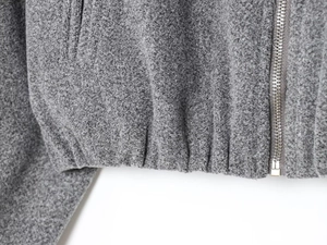 Détail de la veste aviateur grise montrant la texture molletonnée et le zip argenté