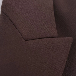 Vue détaillée du tissu marron foncé et des coutures fines sur le col du costume chic