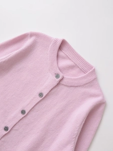 Detailed close-up of light pink knit cardigan with round neck and five grey buttons