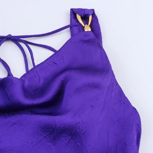 Dettaglio dell'abito midi in raso viola con fibbia a cuore dorata e spalline intrecciate