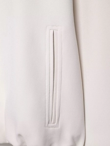Détail d'une poche passepoilée verticale sur une veste en sergé beige aux coutures nettes