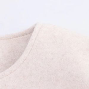 Close-up detail of soft oatmeal wool texture on a minimalist bomber jacket shoulder