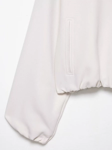 Détail de la veste blanc cassé montrant l'ourlet élastique et la poche latérale