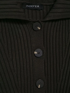Détail de la maille côtelée et des boutons marbrés sur un cardigan vert foncé