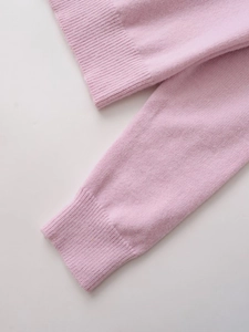 Detailed macro view of the ribbed cuffs and hem on a soft pale pink knit cardigan