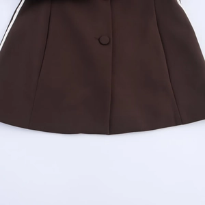 Détail de gilet marron foncé avec bande latérale blanche et bouton recouvert assorti