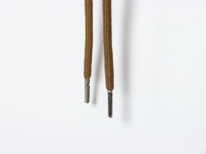 Macro detail of brown woven drawcord with premium silver metal aglets on a jacket