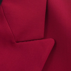 Close-up of the notch lapel and premium woven texture on a dark red blazer jacket