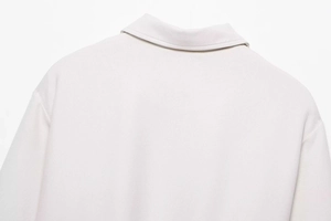 Détail de la couture du col et de l'épaule sur une veste zippée de couleur blanc cassé