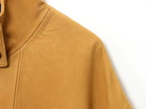 Close-up of ginger leather aviator jacket showing premium grain texture and fine stitching