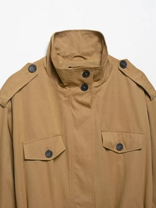 Detail view of khaki trench coat featuring high collar buttons and military shoulder epaulettes