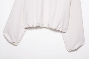 Vue détaillée du sweat à capuche crème avec ourlet élastique froncé et poignets côtelés