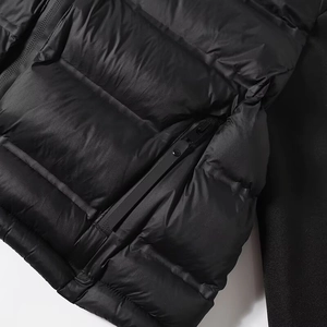 Détail de la doudoune noire présentant une texture matelassée et un zip étanche