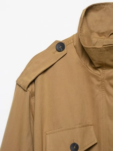 Close-up of khaki trench coat details featuring shoulder epaulettes and flap pockets