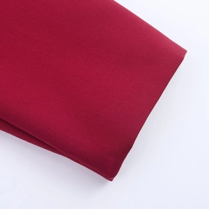 Detail shot of folded burgundy textile fabric showing fine weave texture and material thickness