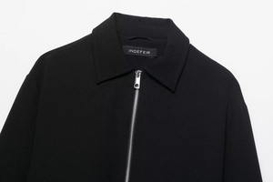 Détail de la fermeture éclair métallique et du col rabattu sur veste noire matelassée
