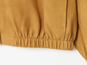 Detail of the elastic pleated hem and lychee grain leather texture of the yellow jacket