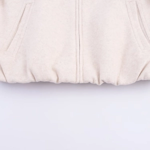 Detailed macro view of soft off-white fleece bomber jacket hem with pockets and zipper