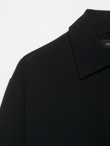 Détail du col à revers noir et des coutures d'épaules de cette veste bouffante chic